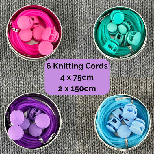 Six knitting stitch holder cords cords in  pink, sea green, purple, and light blue, arranged in round metal tins with 6 stoppers, on a gray knitted fabric background. A purple text box in the centre reads '6 Knitting Cords 4 x 75cm 2 x 150cm'.