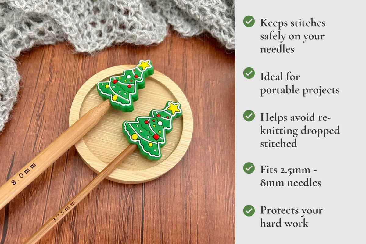 Two wooden knitting needle stoppers  shaped like Christmas trees in green and yellow, displayed on a round wooden coaster  on a dark wood table with a gray knitted blanket. A text panel on the right lists product features with green check marks saying Keeps stitches on needles. Ideal for portable projects. Helps avoid re-knitting dropped stitches. Fits mm to 2.5mm to 8mm needles 
