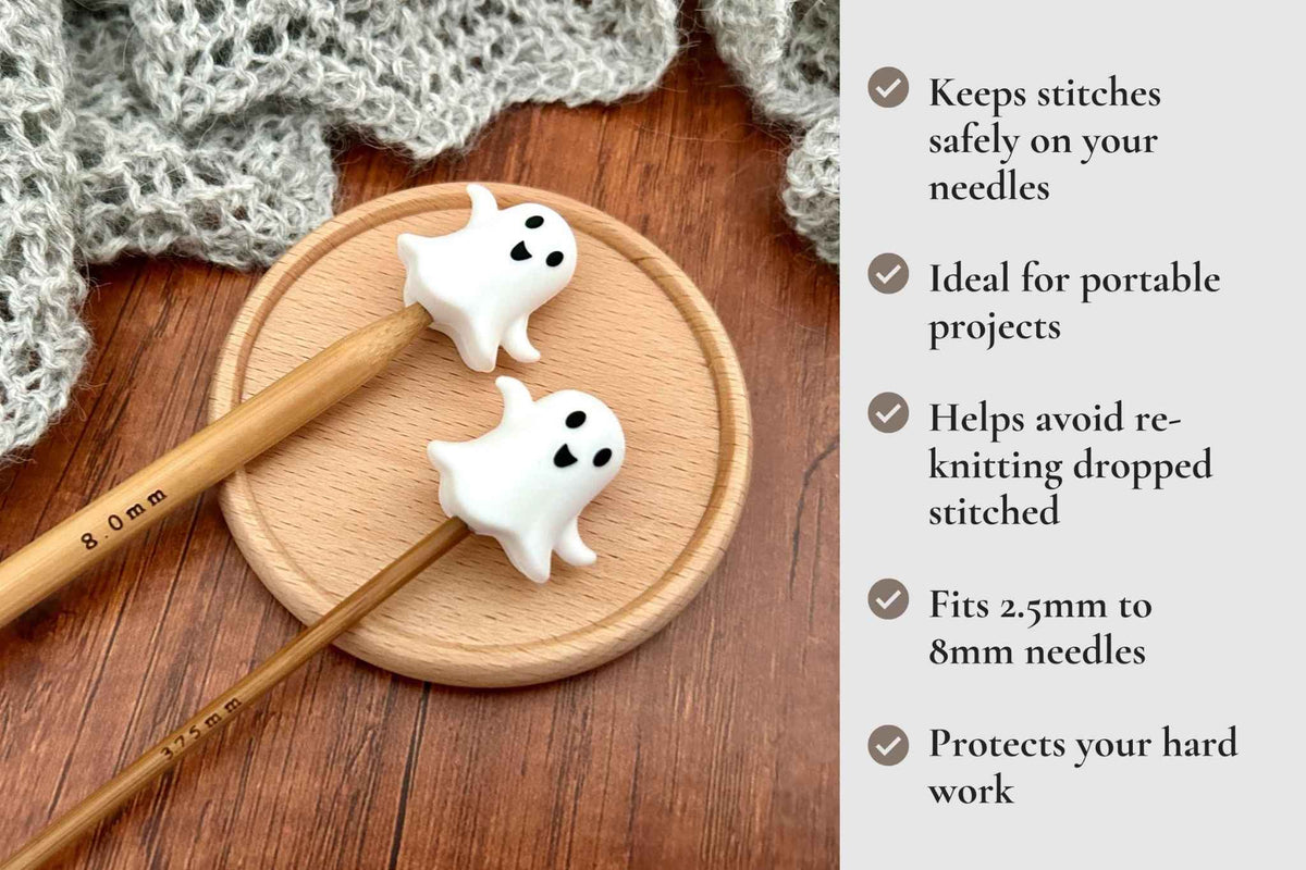 A promotional graphic for a ghost-shaped knitting needle guard. The image shows two white ghost-shaped protectors on wooden knitting needles, resting on a round wooden coaster with a knitted scarf in the background. Keeps stitches on needles. Ideal for portable projects. Helps avoid re-knitting dropped stitches. Fits mm to 2.5mm to 8mm needles 
