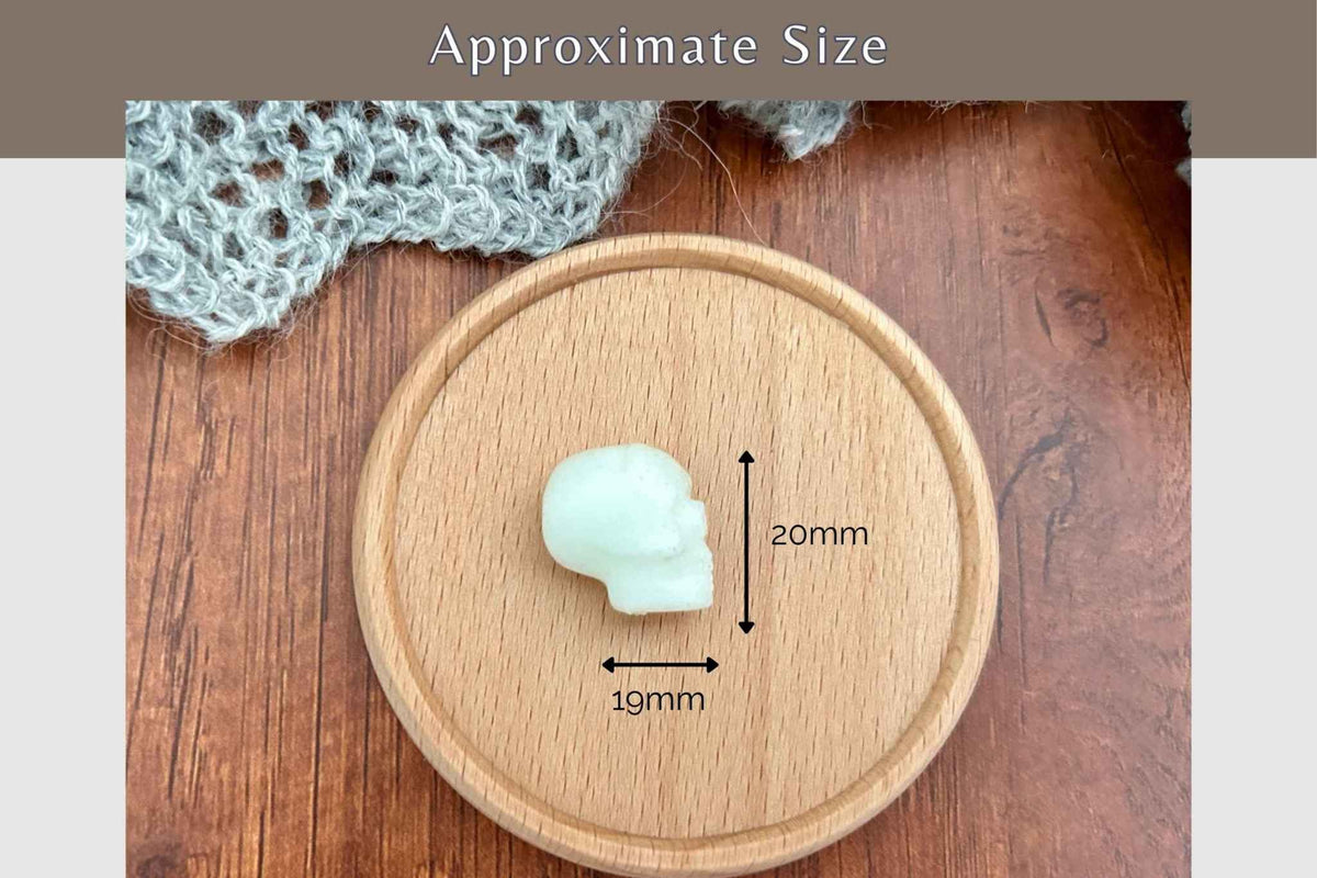 A single skull shpped needer stopper placed on a round wooden tray, with overlaid dimension arrows and text reading 20mm tall and 19mm wide, plus a top banner that says Approximate Size.