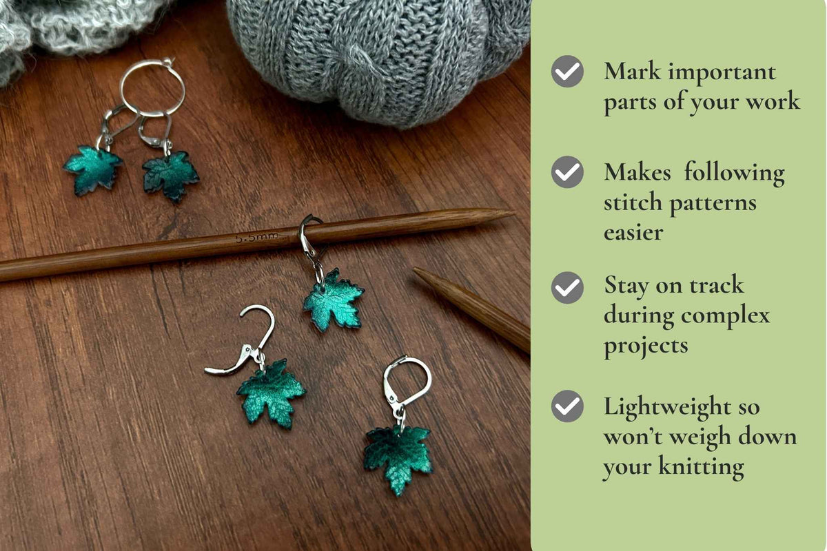Five maple leaf-shaped stitch markers with teal green glitter accents are arranged on a wooden surface alongside knitting needles and a gray knitted ball. A light green text panel on the right lists benefits of using these stitch markers. Mark important parts of your work. Makes following stitch patterns easier. Removable so works for knitting and crochet. Stay on track during complex projects.
