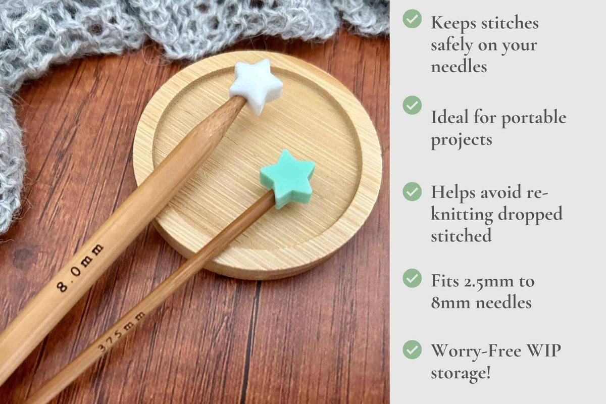 Two wooden knitting needles with star-shaped tips in white and mint green, displayed on a round wooden tray over a wood surface next to a gray knitted scarf. A text panel on the right lists product benefits. Keeps stitches on needles. Ideal for portable projects. Helps avoid re-knitting dropped stitches. Fits mm to 2.5mm to 8mm needles 

