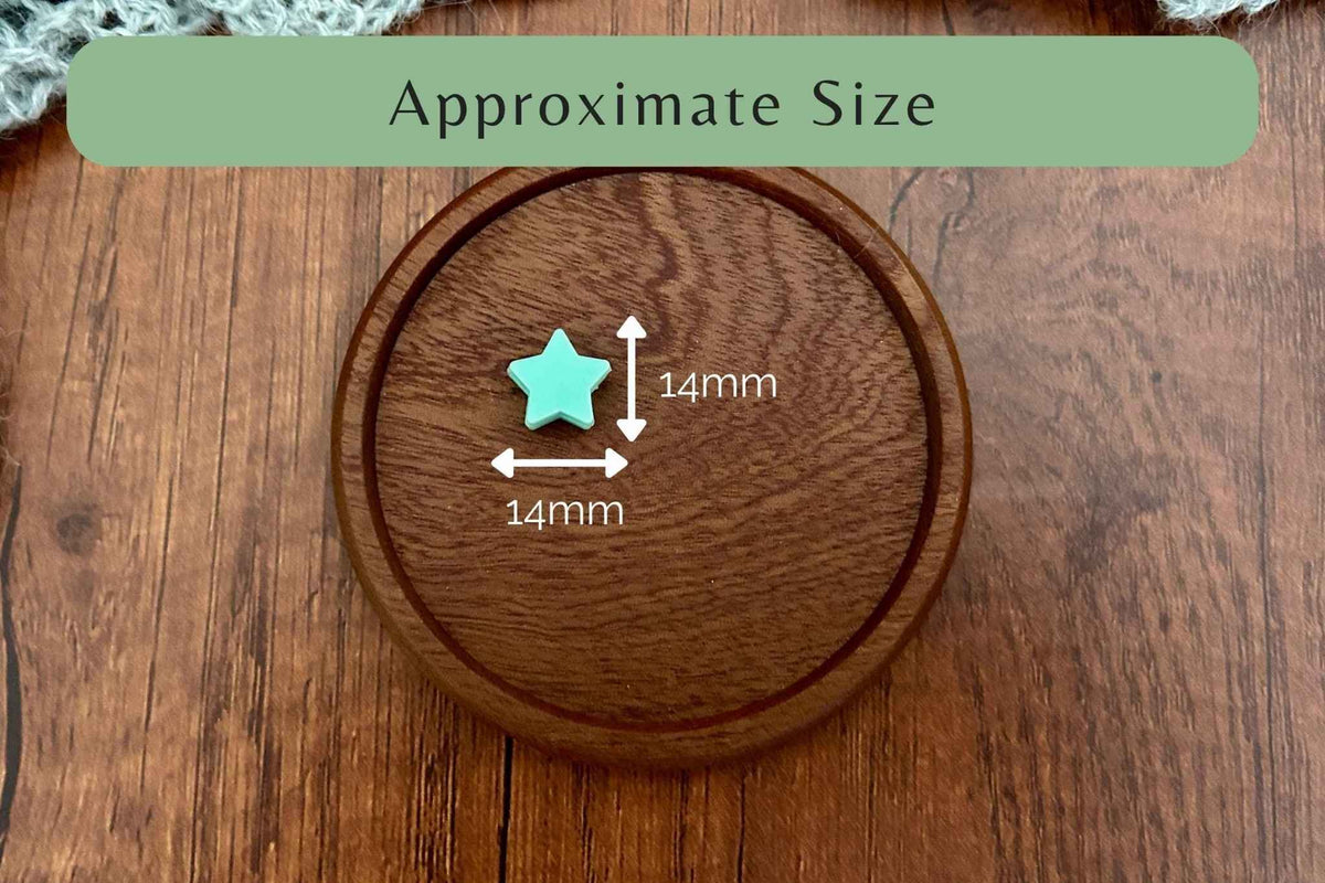 A small mint green star-shaped stitch saver shown on a wooden surface with overlaid dimension labels reading 14mm by 14mm and a green banner at the top that says Approximate Size.