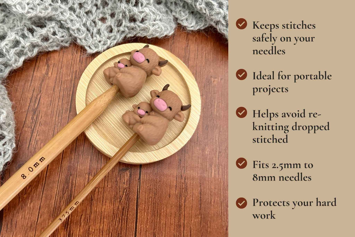 Two wooden knitting needles with highland cow-shaped stitch protectors rest on a round wooden tray, with a knitted fabric nearby and a text panel on the right describing benefits. Keeps stitches on needles. Ideal for portable projects. Helps avoid re-knitting dropped stitches. Fits mm to 2.5mm to 8mm needles 