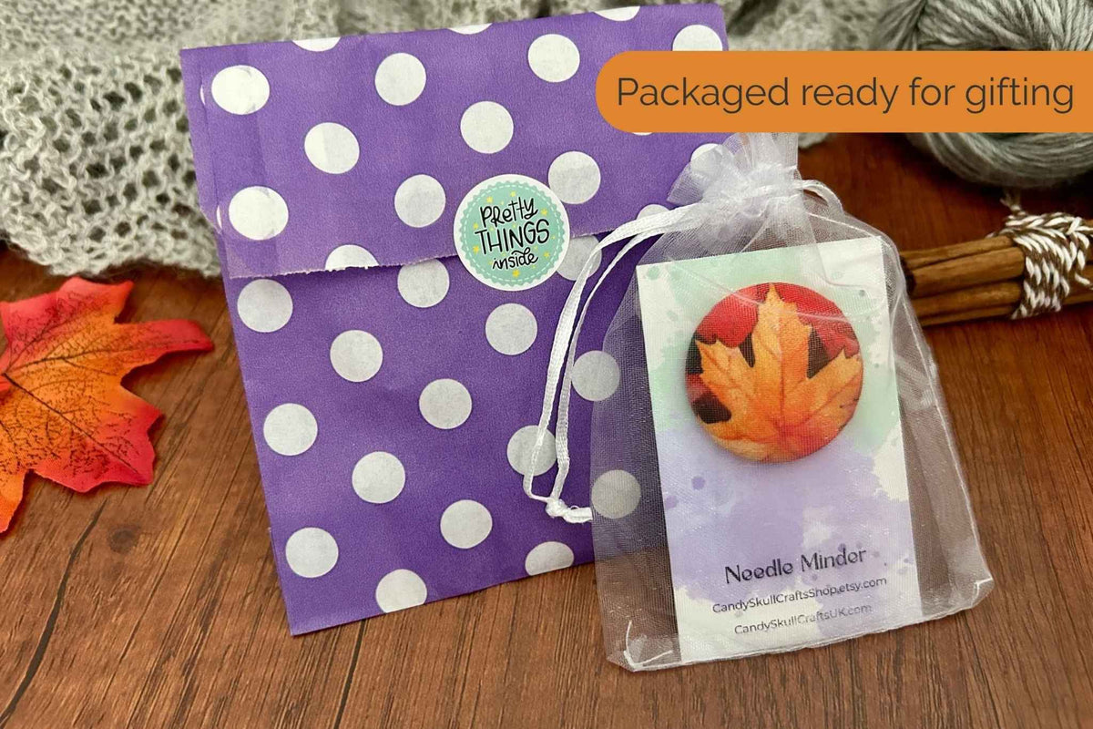 A magnetic needle minder featuring an autumn maple leaf packaged in an organza bag. The packaging is a purple and while polka dot bag.