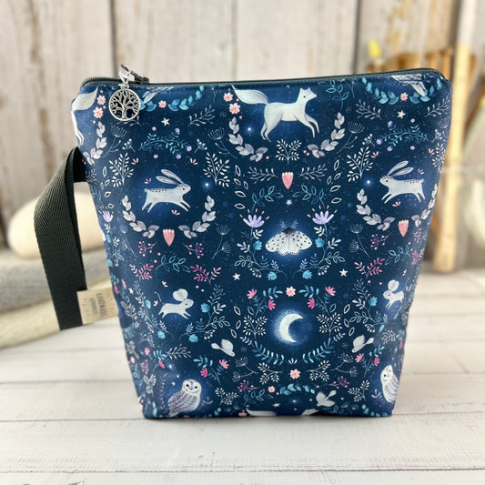 A dark blue knitting or crochet project bag with grey handle & zip. The fabric features nocturnal woodland animals - a hare, fox, moth, and owl