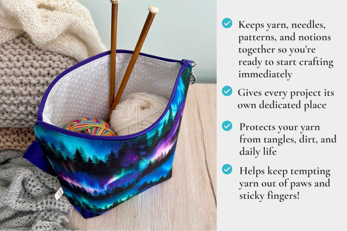 A zippered yarn storage knitting or crochet project bag with a colourful forest landscape print, shown on a tabletop with knitting needles, yarn balls, and knitted blankets. A text panel on the right lists product features with check marks. It readds "keeps yarn, needles, patterns & notions together, gives every project its own dedicated space, protects yarn from tangles, dirt & daily life, helps keep tempting yarn out of paws & sticky fingers"
