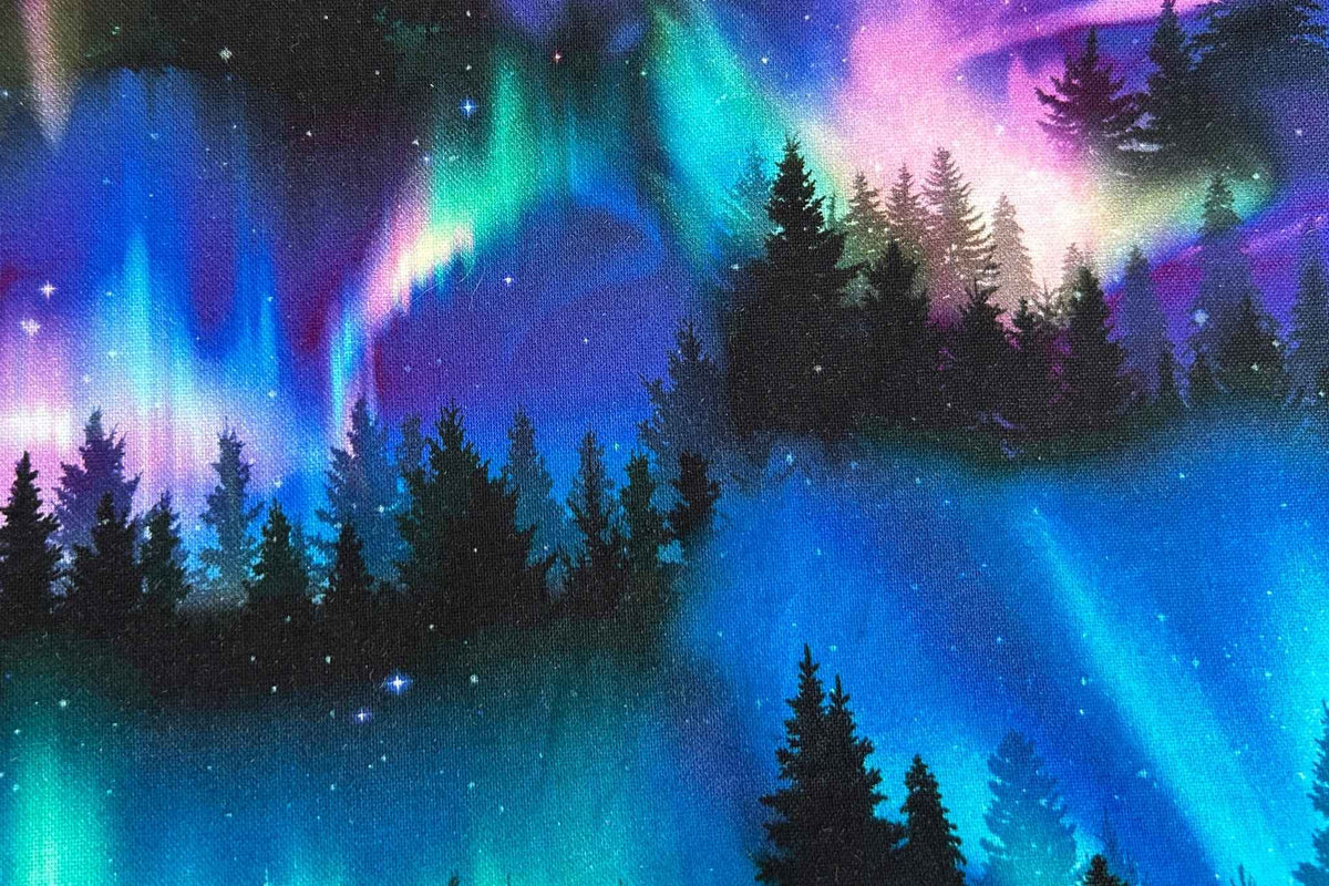 a close up of the fabric showing the aurora borealis with swirling bands of blue, teal, purple, and pink over silhouetted pine trees and a starry night sky.